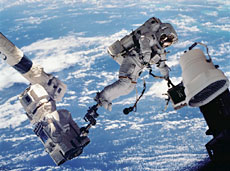 ロボットアームの先端に乗って作業する宇宙飛行士(提供:NASA)